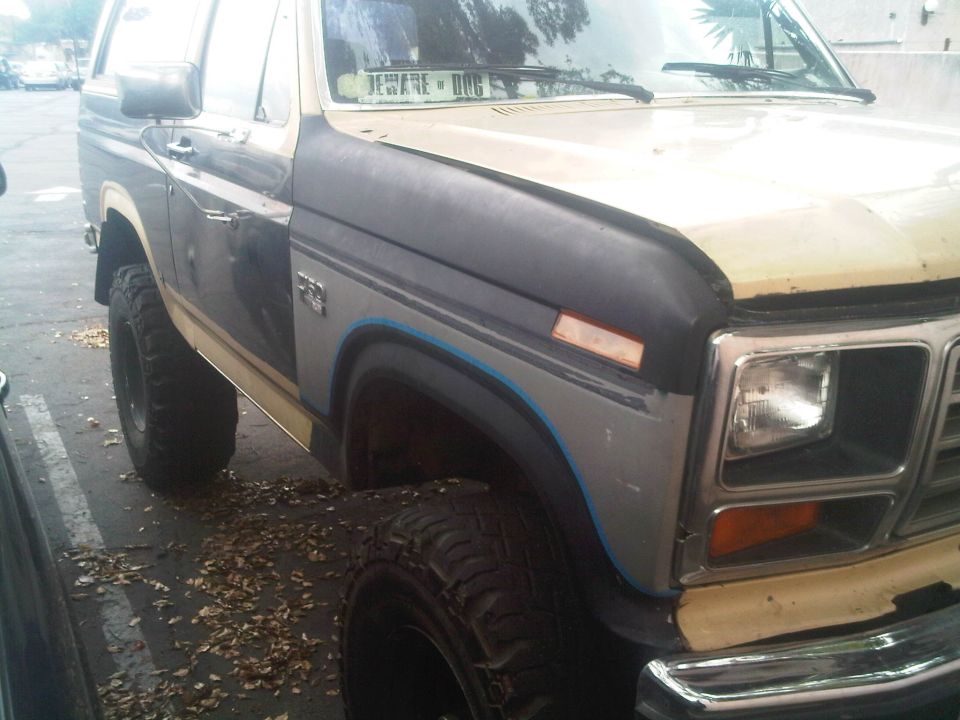 Close-up of a 1980s Ford Bronco's front fender and quarter panel, showing aftermarket modifications and wear