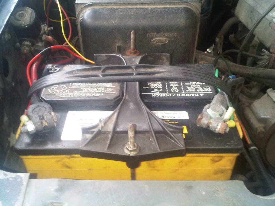 Engine bay with yellow-cased battery and red and yellow wires