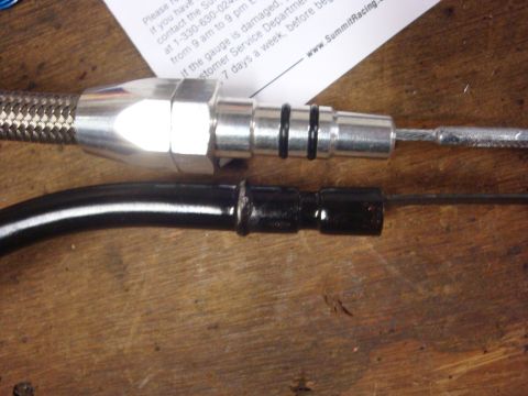 1989 Ford Bronco - Braided hose fitting and dipstick shown on a wooden workbench with a document.