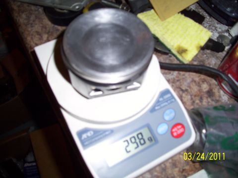 1995 Ford Probe - A piston is weighed on a digital scale, displaying 298 grams.