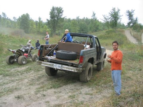 1986 Ford Bronco - A 1986 Ford Bronco is parked off-road with a child in the back, an ATV, and several people nearby.