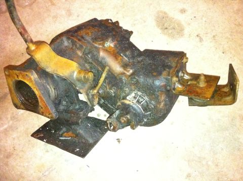 1989 Ford Bronco - A heavily rusted transfer case component with visible levers and a metal bracket attached.