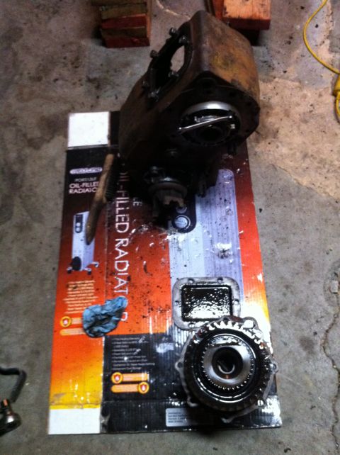 1989 Ford Bronco - Transfer case parts are laid out on a radiator box, possibly for repair or identification.