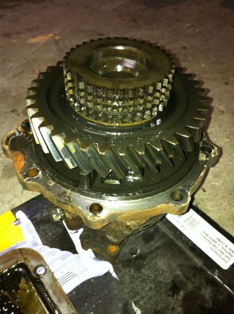 1989 Ford Bronco - Close-up of a transfer case gear assembly, showing internal components and a partial label on the tray below.