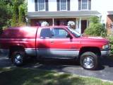 1989 Ford Bronco - Side view of a red 1994 Dodge Ram pickup truck equipped with a camper shell.