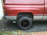 1989 Ford Bronco - The rear wheel and exhaust pipe of a red pickup truck are visible in this close-up shot.