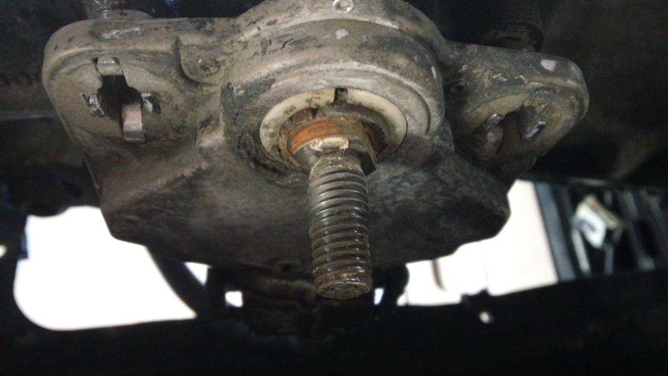 Close-up of a suspension component with a bolt and Supermotors.net logo