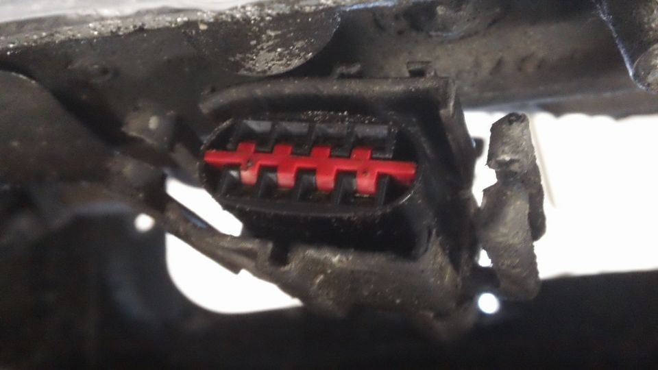 Close-up of a black electrical connector with red internal pins