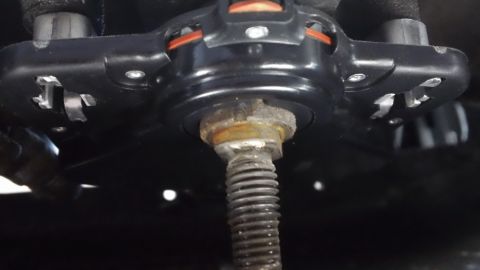 1994 Ford Bronco - A close-up view of a vehicle's suspension component, showing a rusty bolt and mechanical parts.