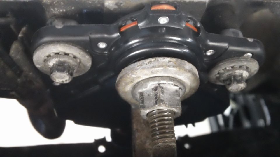 Close-up of a suspension component with bolts and a large nut
