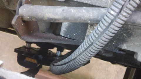 1994 Ford Bronco - A close-up view of a vehicle's undercarriage shows an electrical connector and a ribbed protective conduit for wiring.