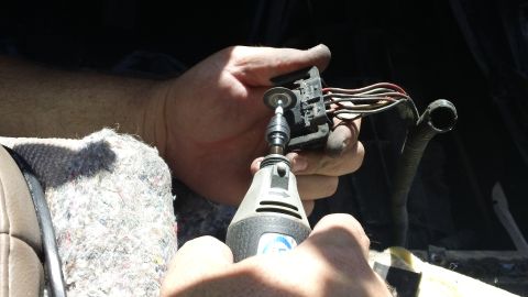 1994 Ford Bronco - Close-up of hands modifying an electrical connector with a rotary tool, likely for a repair or modification.