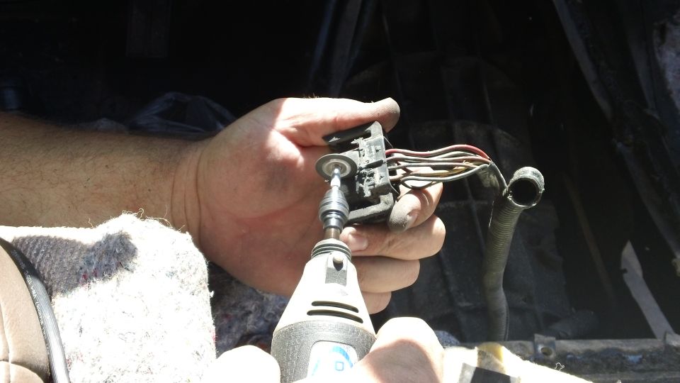 Hand holding electrical connector with wires, using a rotary tool to modify it