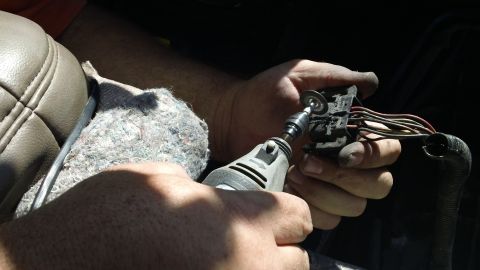 1994 Ford Bronco - A close-up shows a person repairing a vehicle's electrical connector with a rotary tool.