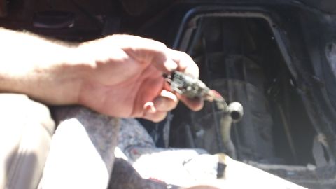 1994 Ford Bronco - A hand holds a damaged electrical connector, likely during a repair, inside a vehicle's interior.