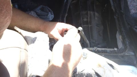 1994 Ford Bronco - Close-up of hands working on a component within a car's interior.