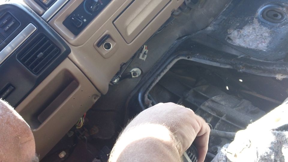 Interior dashboard and center console of a tan and black 1992 Ford Bronco with exposed wiring