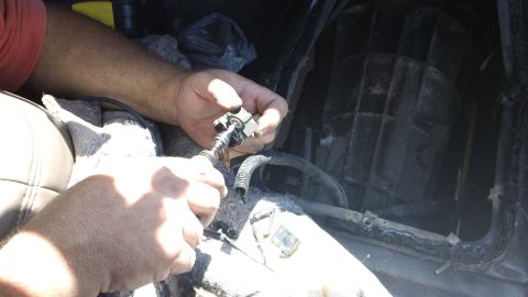 1994 Ford Bronco - A person is shown working on a vehicle's interior, focusing on a small part of the electrical system.