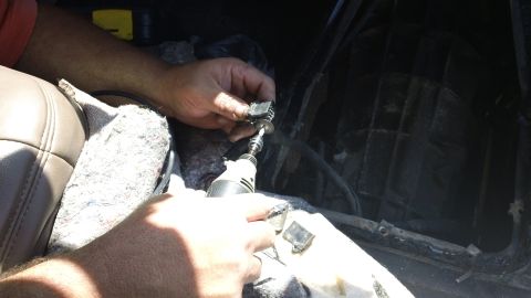 1994 Ford Bronco - A person works on the interior console of a vehicle, with a rotary tool in hand.