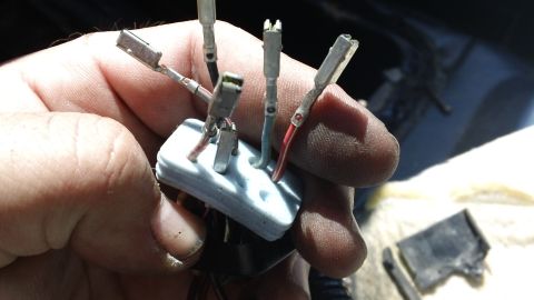 1994 Ford Bronco - Close-up of a hand holding an electrical connector with multiple wires, likely for vehicle repair.