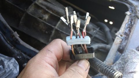 1994 Ford Bronco - Close-up of a hand holding a wiring harness connector with multiple wires exposed.