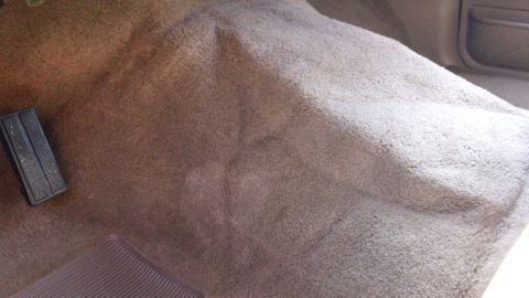 1994 Ford Bronco - Close-up of a car's carpeted floor, showing pedals and a water stain.