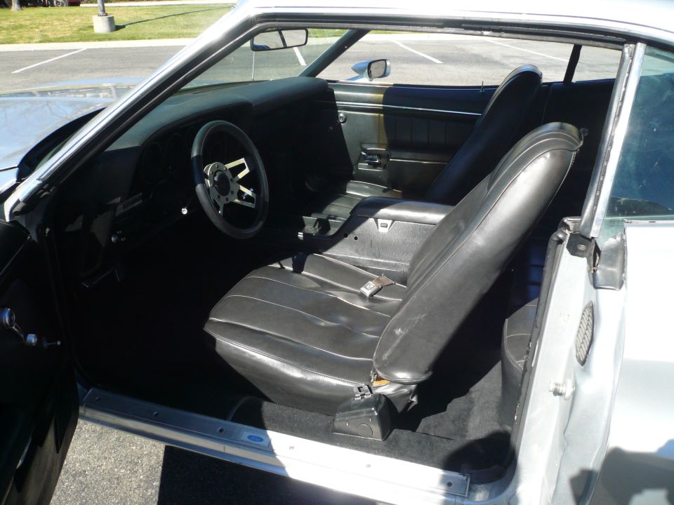 1973 Ford Torino interior with black vinyl seats, aftermarket steering wheel, and dashboard
