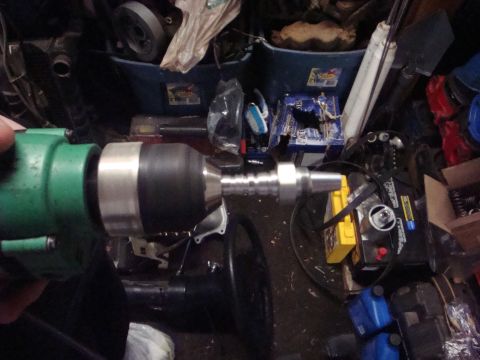 1989 Ford Bronco - A power drill with a metal chuck adapter is held in front of a cluttered background of tools and parts.