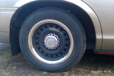 2000 Mercury Grand Marquis - Close-up of a car's wheel and fender, showing a Mercury logo on the hubcap.
