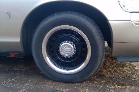 2000 Mercury Grand Marquis - Close-up of a gold Mercury Grand Marquis wheel, a black rim and a chrome hubcap with the Mercury logo.