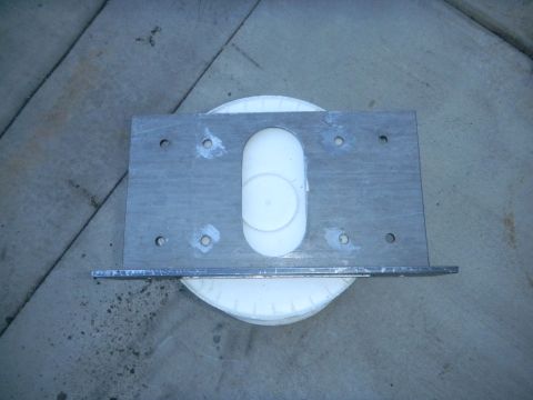 1997 Ford Ranger - A metal bracket with a white plastic insert is shown resting on a white circular object on a concrete surface.