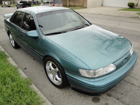 2003 Ford Taurus - This teal sedan is parked on the side of a street, showing its front three-quarter view.