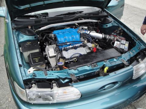 2003 Ford Taurus - The engine bay of a teal car is open, revealing the engine components and a blue intake manifold.