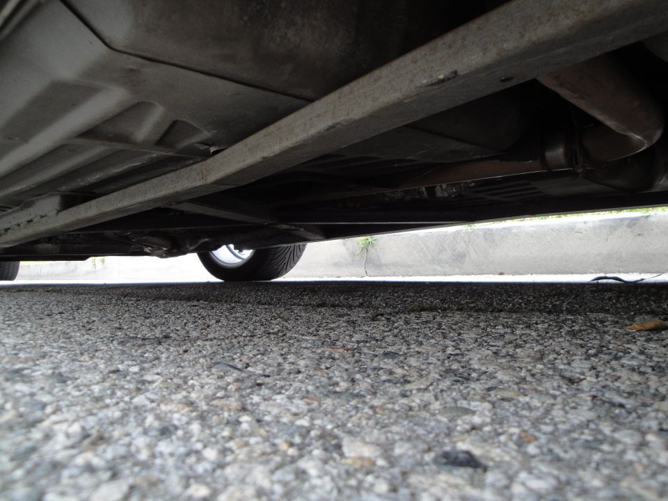 Underside view of a car showing the exhaust system and a tire