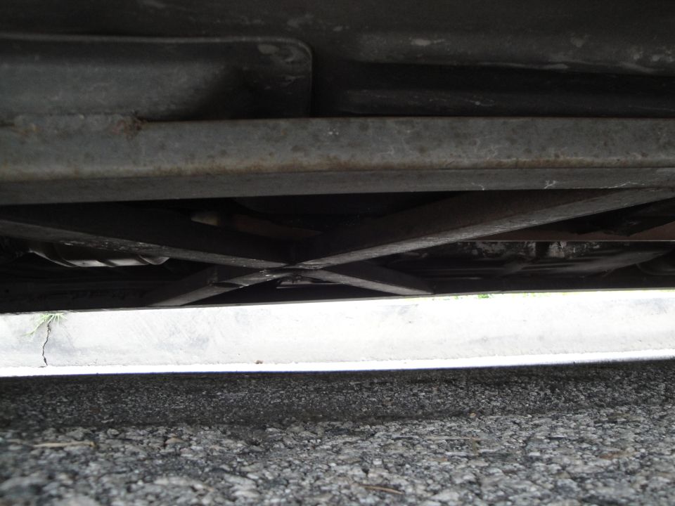 Underside of a car showing structural beams and exhaust pipe