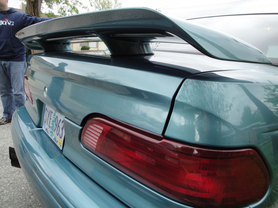 Teal sedan's rear spoiler and taillight. License plate reads SYE 963