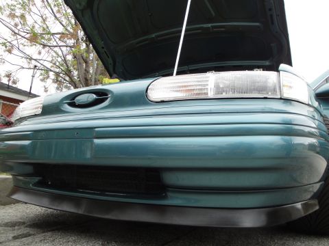 2003 Ford Taurus - The front of a teal sedan is shown with its hood open, revealing the engine bay.