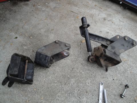 2003 Ford Taurus - Three engine mounts are laid out on a concrete surface. One mount includes a small shock absorber.
