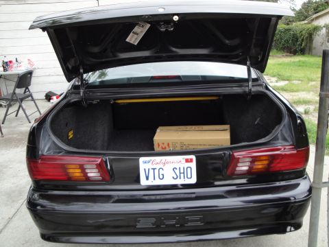 2003 Ford Taurus - Rear view of a black sedan with its trunk open, revealing a box and a California license plate.