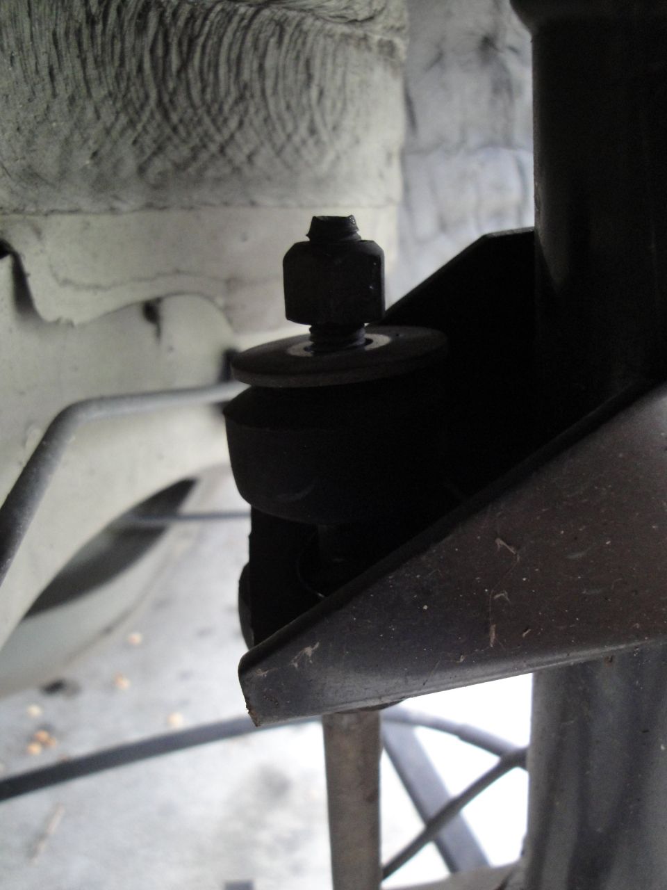 Close-up of a black rubber bushing and bolt on a vehicle's suspension system