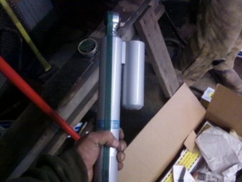 1995 Ford Bronco - A person holds a shock absorber, possibly for a vehicle, in a cluttered garage setting.