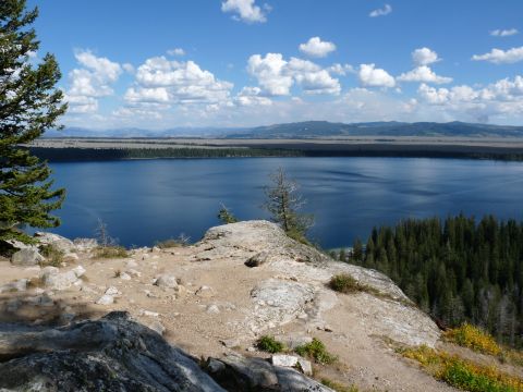 2006 Ford E350 - A wide view of a large lake surrounded by forests and mountains, seen from a rocky vantage point.