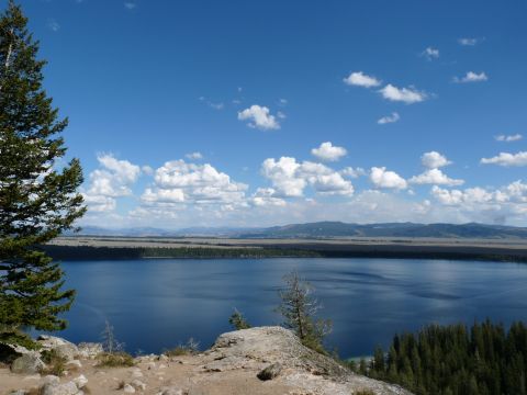 2006 Ford E350 - A vast blue lake is surrounded by trees and mountains under a bright, cloudy sky, offering a natural vista.