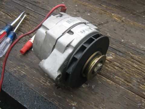 1972 Ford F-250 - An alternator sits on a weathered wooden surface next to a pair of screwdrivers.