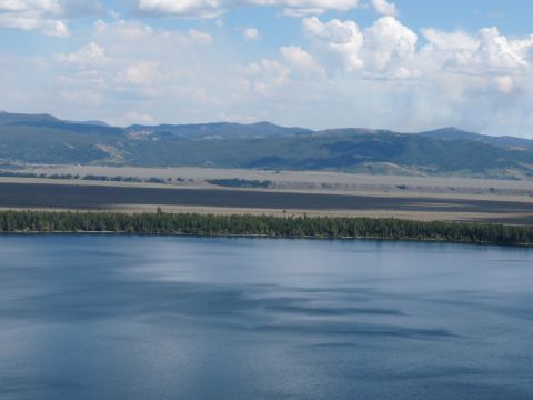 2006 Ford E350 - A landscape a calm lake, a dense forest, and distant mountains under a partly cloudy sky.