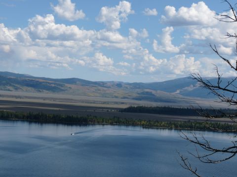 2006 Ford E350 - A boat travels across a large lake with mountains in the background.