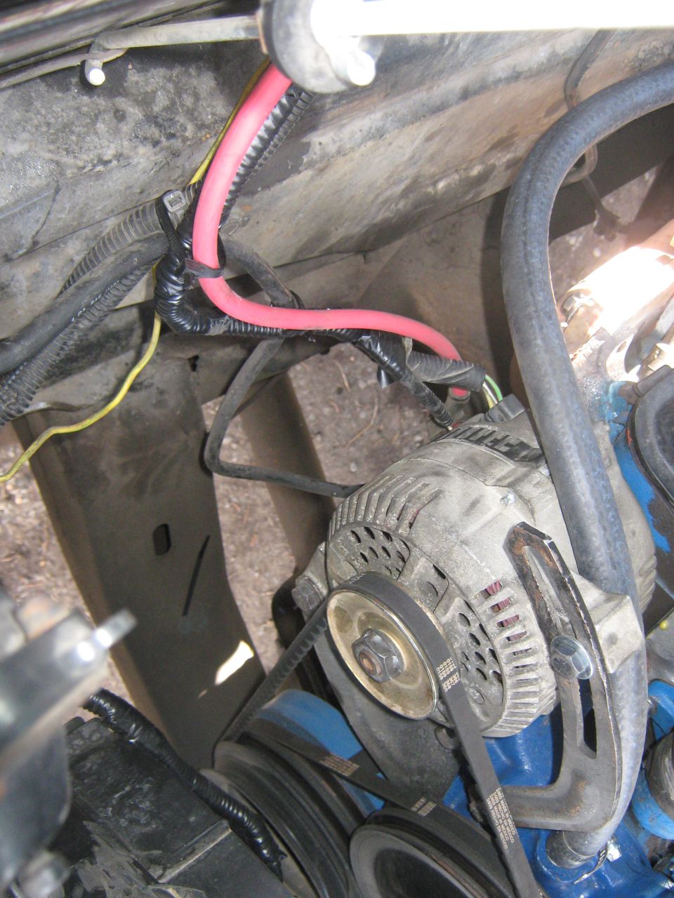 Alternator with red and black wiring in engine bay. Text 'SUPERMOTORS' visible