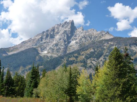 2006 Ford E350 - Mountain landscape with dense forestation and dramatic rocky peaks under a partly cloudy sky.