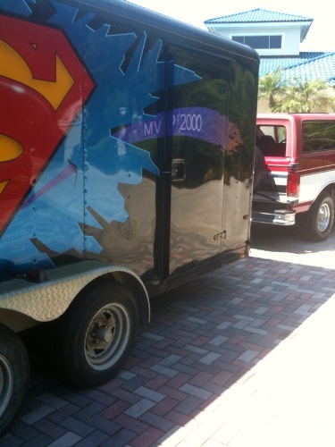 1995 Ford Bronco - A trailer with a Superman logo is parked next to a red and white SUV.
