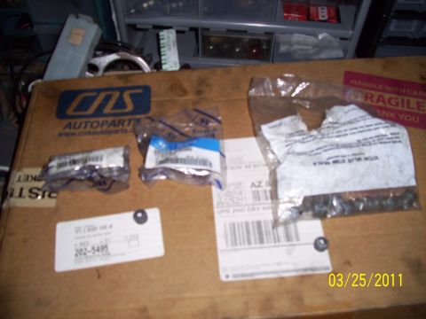 1995 Ford Probe - Several automotive parts are laid out on a cardboard box, some in original packaging, with a date stamp of 03/25/2011 visible.